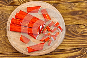 Crab sticks on cutting board on wooden table