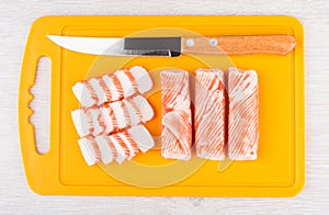 Crab sticks and kitchen knife on orange cutting board