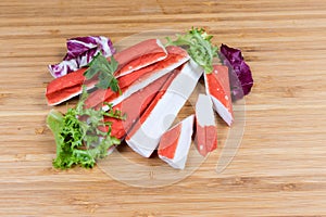 Crab sticks and variegated lettuce leaves on cutting board