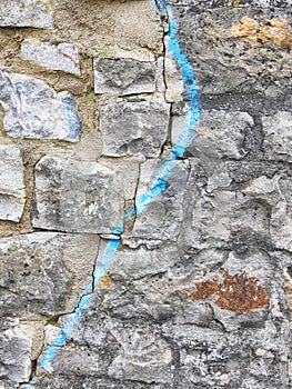 Crack on a brick stone wall with blue paint