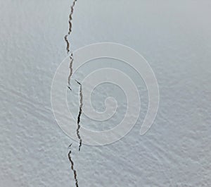 A crack in the gray wall of the house