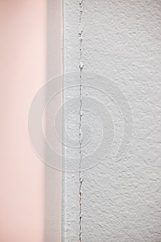 A crack in the greige wall where the sheetrock meets at the corner in a new construction house needing repairs