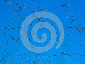 The crack surface of glass window with blue sky color at the background.