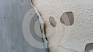 Crack on the wall of the house. Old plaster falls off the surface. Defect during construction. The effect of humidity on the