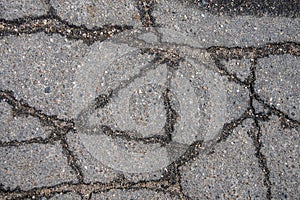 Cracked asphalt in the city, cracks and potholes on the road, textured road surface, selective focus.