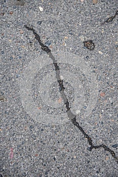 Cracked asphalt in the city, cracks and potholes on the road, textured road surface, selective focus.