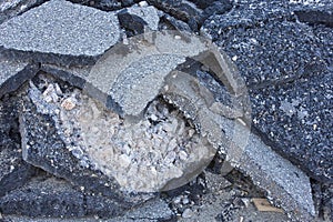 Cracked asphalt pieces after demolition of a road surface in a construction site for renovation ready to be recycled