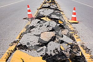 Cracked asphalt road with marking lines and safty cones