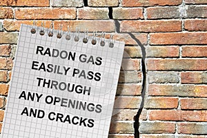 A cracked brick wall with warning message about radon gas escaping through cracks and openings - concept image