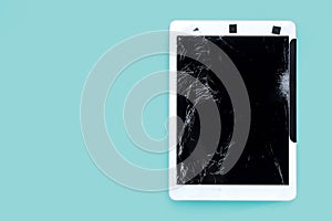 Cracked or broken screen of smartphone or tablet temporarily fixed with black tape on green pastel background
