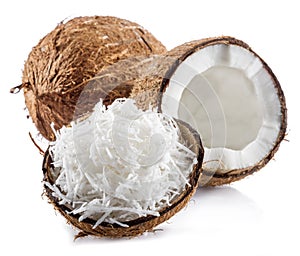 Cracked coconut fruit with white flesh and shredded coconut flakes isolated on white background