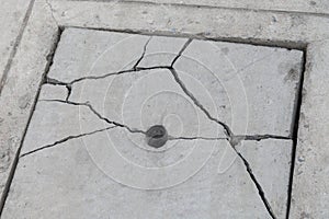 Cracked concrete drain cover on the cement road