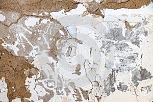 Cracked and crumbling plaster from a white wall - a wallpaper pattern or work for a construction team to repair an old building.