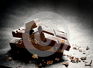 Cracked dark chocolate bar at black background