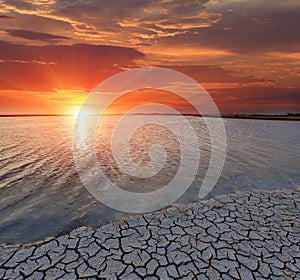 Cracked earth seacoast on sunset background