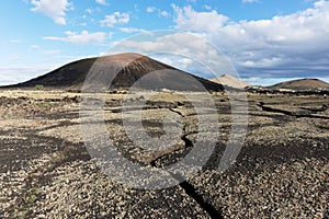 Cracked earth in Timanfaya National Park, mountains in the background. Lanzarote