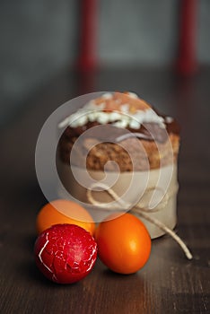 Cracked Easter egg with other colored eggs and Easter cake on wooden table