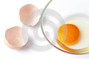 Cracked egg with egg shell, egg yolk and egg in glass bowl isolated on white background