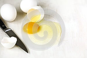 Cracked egg with egg shell, egg yolk and egg white on white background