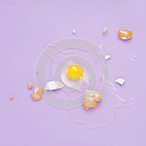 Cracked egg, eggshell with yolk isolated on purple background. Broken idea concept.