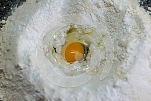Cracked egg in flour, ready for dough mixing close-up