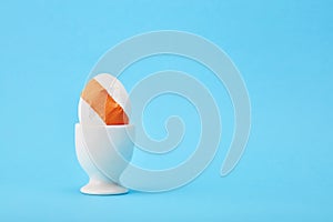 Cracked egg with medical patch in an egg cup on blue background