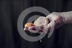 Cracked egg yolk in a woman`s hand, close up, still life photography