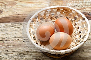 Cracked eggs in a wicker plate on a wooden table.