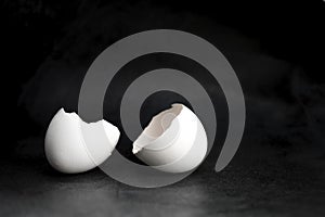 Cracked eggshell on a black background. Broken egg in half.