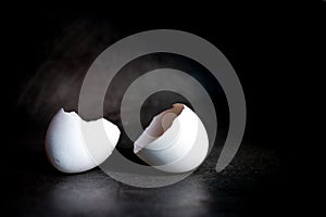 Cracked eggshell on a black background. Broken egg in half