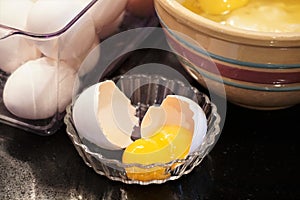 Cracked eggshell with double yolk egg next to vintage stoneware bowl