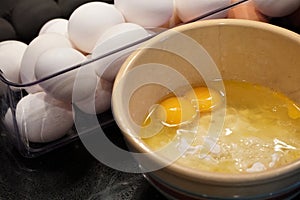 Cracked eggshell with double yolk egg next to vintage stoneware bowl