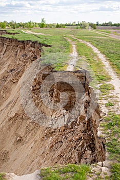 Cracked embankment of the river, road ends in abyss