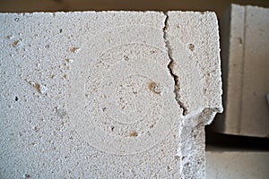 Cracked freshly delivered aerated concrete brick close-up. White porous brick with a chipped piece, fragile building materials