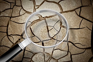 Cracked ground seen through a magnifying glass - The effects of drought - Concept image