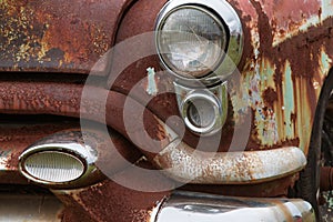 Cracked Headlight And Chipped Paint On Old Rusted Junkyard Car photo