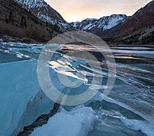 Cracked ice on a frozen lake captures sunset light