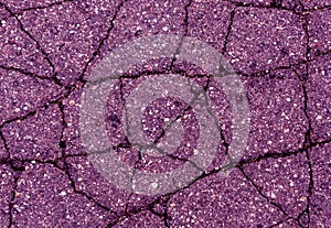 Cracked magenta asphalt surface.