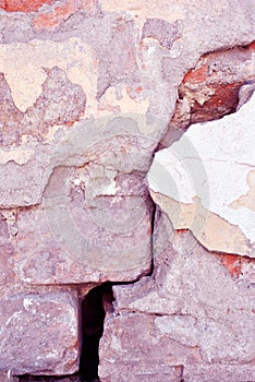 Cracked paint, plaster of soft yellow-red pastel color on brick wall surface close up detail, grunge vertical background