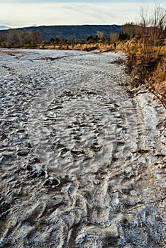 Cracked red clay and white salt on the surface in a dried riverbed in the desert of New Mexico, USA