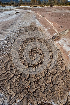 Cracked red clay and white salt on the surface in a dried riverbed in the desert of New Mexico, USA