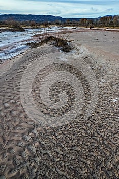 Cracked red clay and white salt on the surface in a dried riverbed in the desert of New Mexico, USA