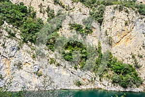 Cracked rock with green plants and trees in a natural park congost de Mont-rebei Monrebey in Spain with blue river, gorge and