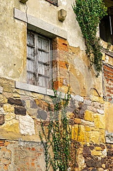 Cracked ruin with a damaged wall and a window with closed wooden shutters