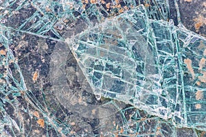 Cracked and shattered glass. Abstract texture and background. Broken glass close-up on the ground