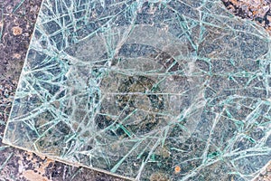 Cracked and shattered glass. Abstract texture and background. Broken glass close-up on the ground
