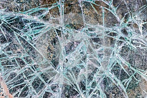 Cracked and shattered glass. Abstract texture and background. Broken glass close-up on the ground