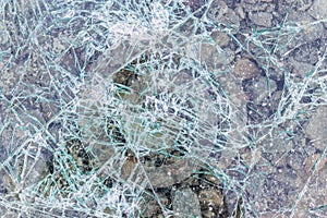 Cracked and shattered glass. Abstract texture and background. Broken glass close-up on the ground