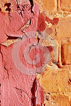 Cracked soft pink paint, plaster surface on yellow brick wall, grunge vertical shabby background detail