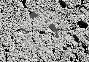 Cracked, textured concrete surface featuring small pebbles embedded in the material.